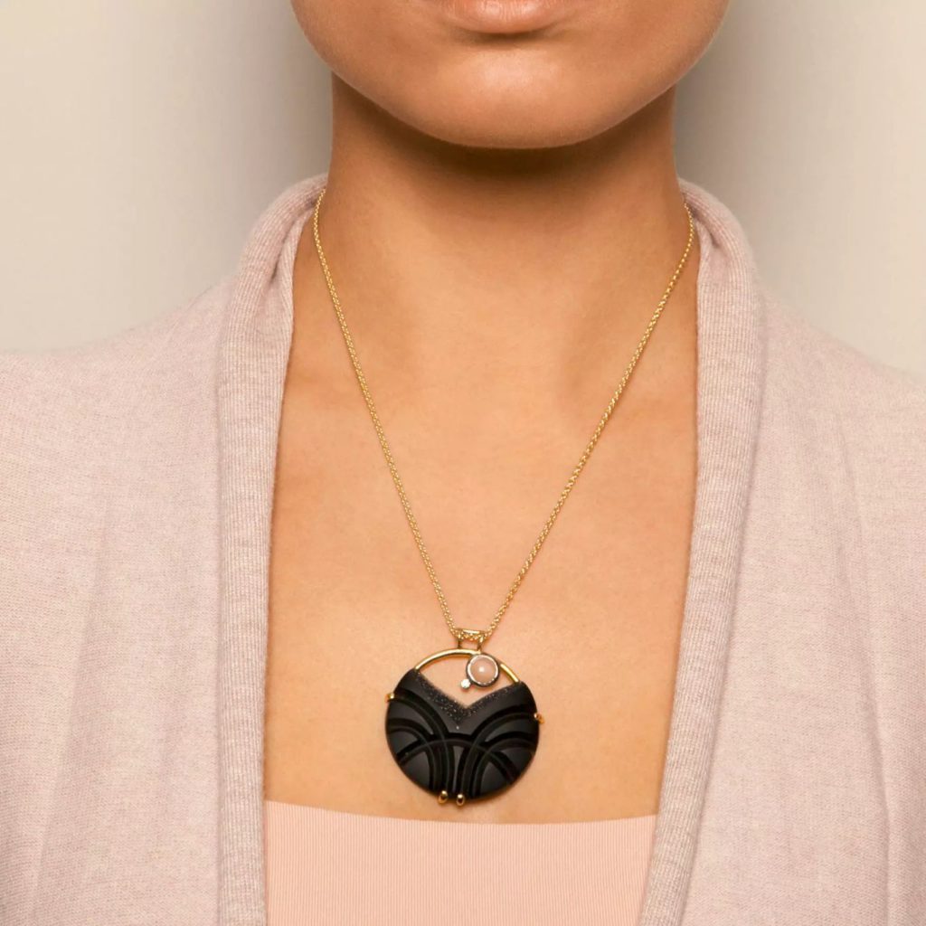 Model wearing Nicole van der Wolf 18k yellow and white gold carved onyx druze pendant with moonstone and diamond.